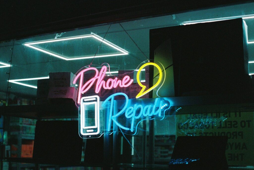 Neon "phone repair" sign with smartphone icon of a smartphone.